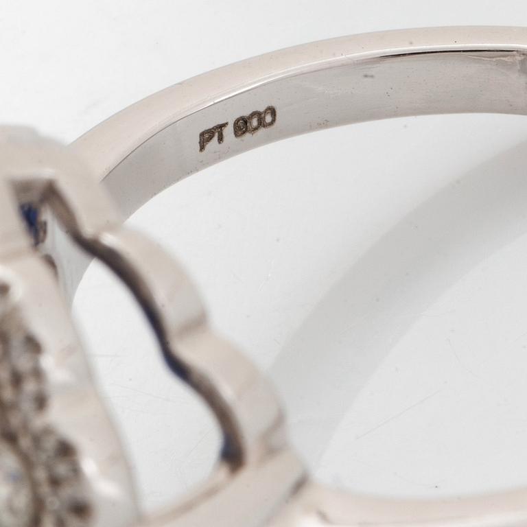 A platinum ring set with a faceted sapphire and round brilliant-cut diamonds.