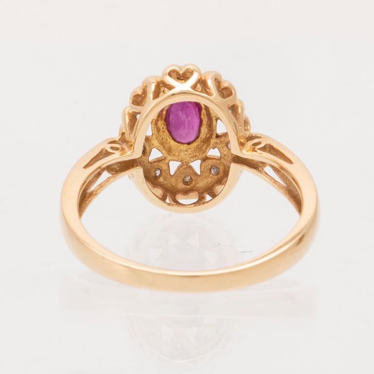 An 18K gold ring set with an oval brilliant cut ruby and round brilliant cut diamonds.