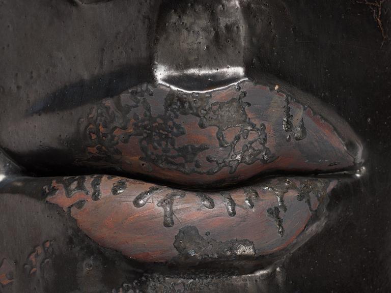 Hertha Hillfon, a black glazed stoneware wall sculpture in two parts of a face and a sky, executed in her own studio, Stockholm 1960s.