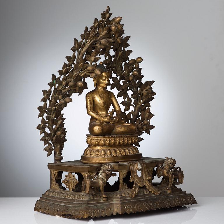 A large Nepalese gilt bronze buddha on a throne with mandorla, 18/19th Century.