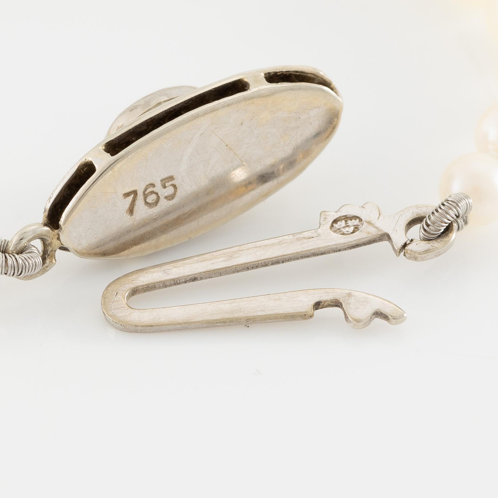 Collier med doserade odlade pärlor, lås 18K vitguld med cabochonslipad smaragd.