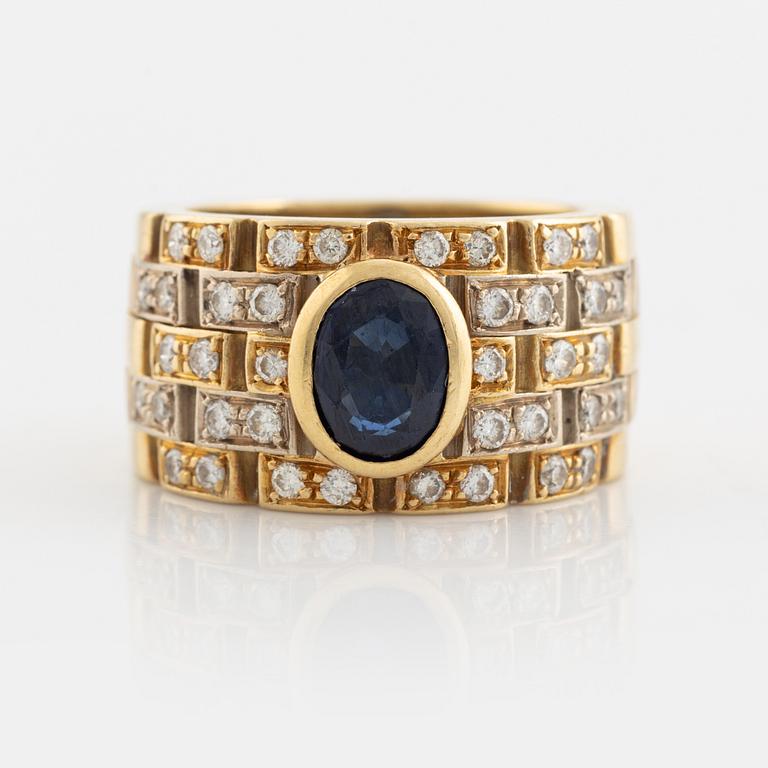 An 18K gold ring set with a faceted sapphire and round brilliant-cut diamonds.