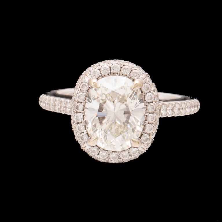 An 18K white gold ring by James Allen, set with an oval brilliant cut diamond in a halo of round brilliant cut diamonds.