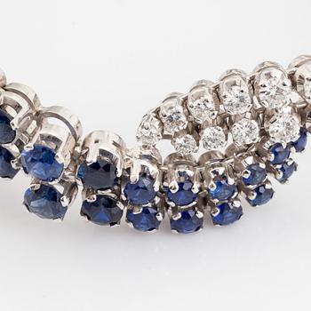 An 18K white gold bracelet set with round brilliant-cut diamonds and sapphires.