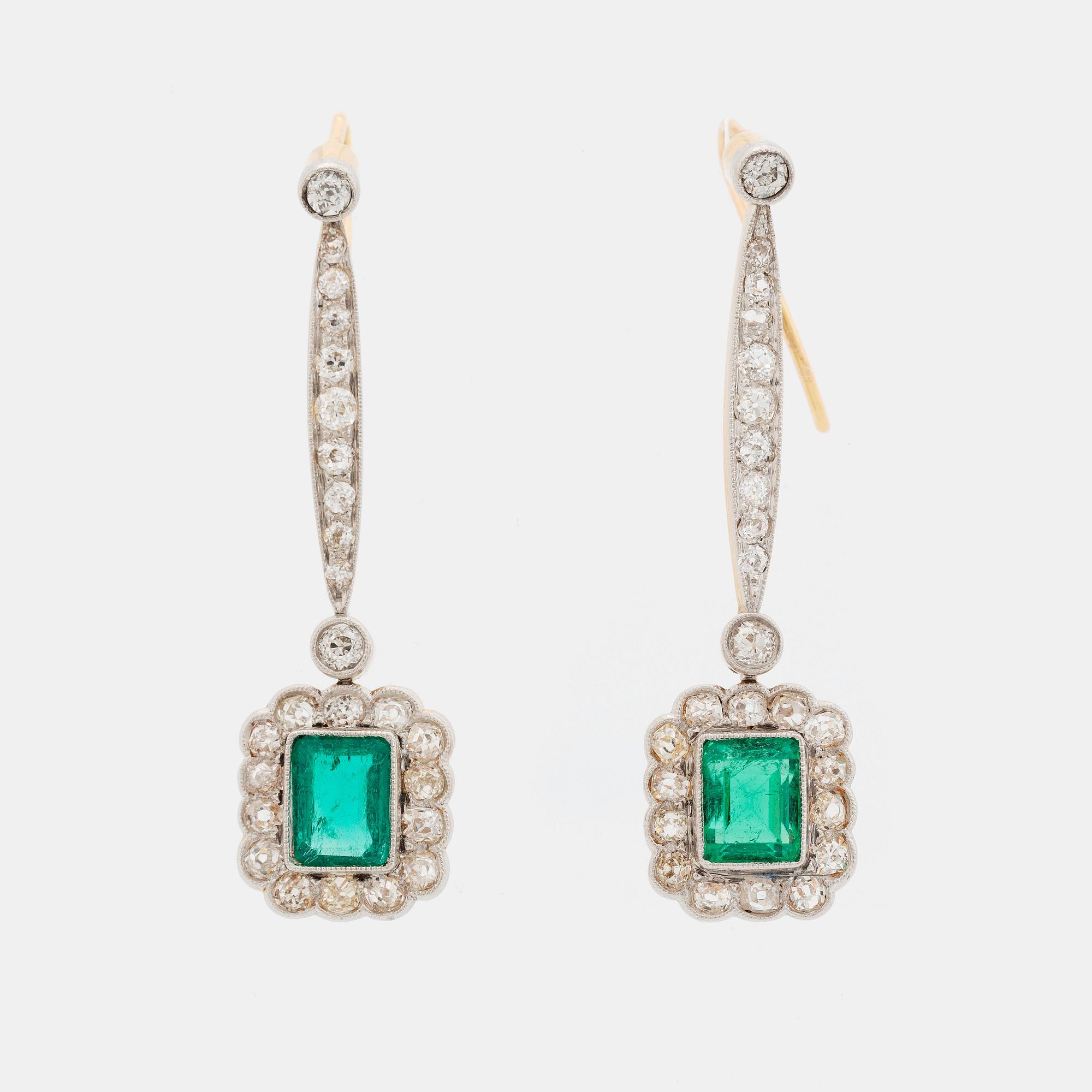 A pair of platinum and gold earrings set with step-cut emeralds and old-cut diamonds.