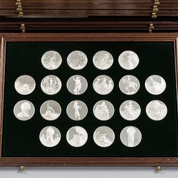 100 sterling silver coins in a wooden cabinet by Franklin Mint.