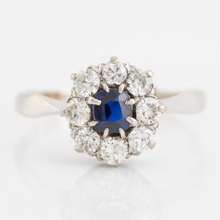 An 18K white gold ring set with a synthetic sapphire and round brilliant-cut diamonds.
