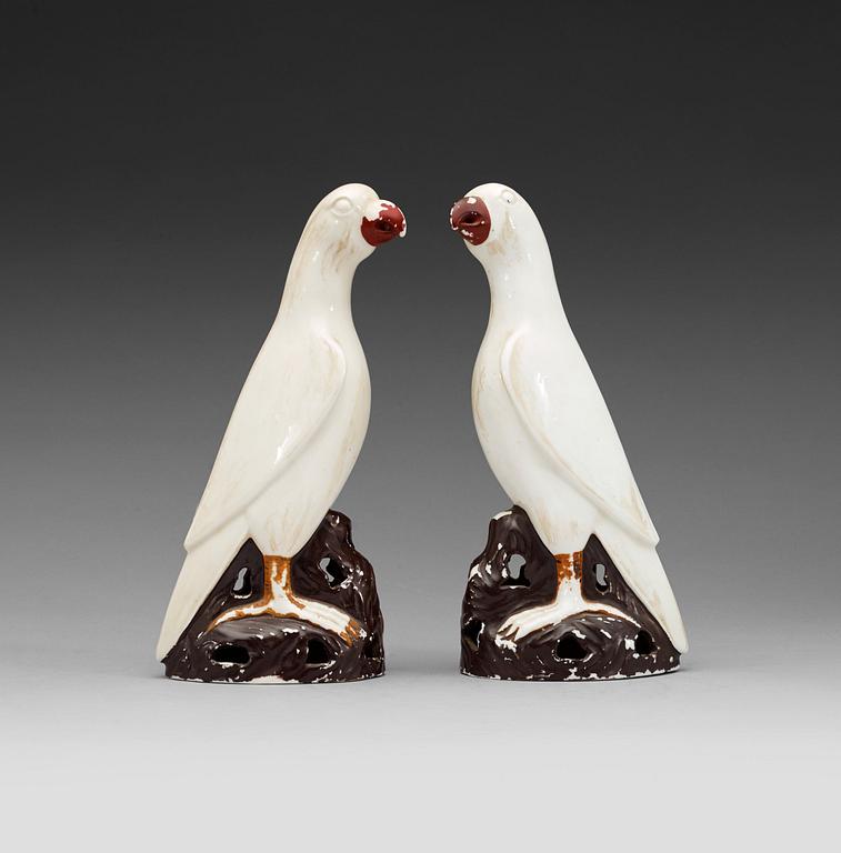 A pair of white andred glazed figures of parrots, late Qing dynasty.