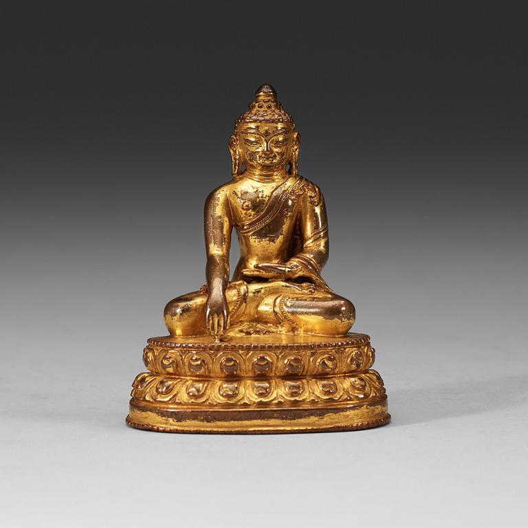 A gilt Tibetan bronze figure of Buddha, 16th Century or older.