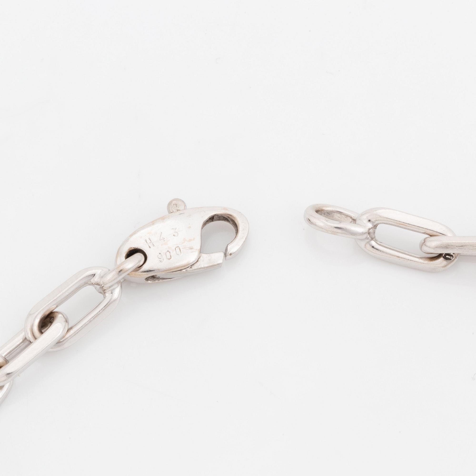An 18K white gold Cartier "Spartacus" bracelet with two charms.