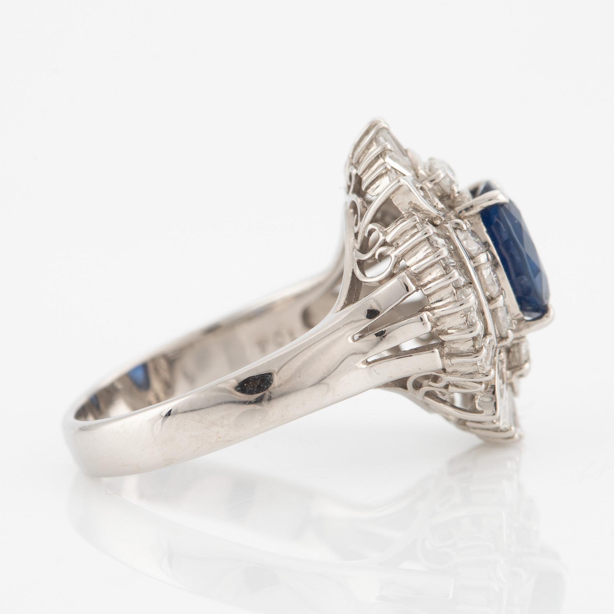 Ring in platinum set with a faceted sapphire and round brilliant- and baguette-cut diamonds.