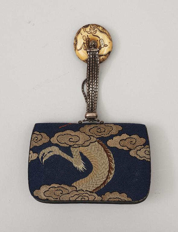 A Japanese embroided tabakoire with a kanamono in the shape of two tigers, a metal chain that holds a carved ivory manjû, second half of 19th Century. Signed.