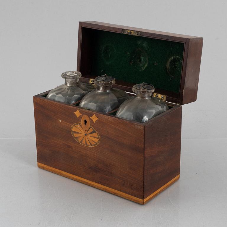 A wooden box with three glass flaska, first half of the 19th century.