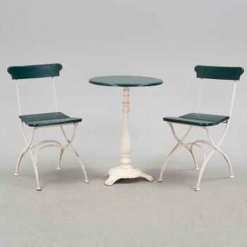 A pair of cast iron chais with wooden seats and a cast iron table, early 20th century.