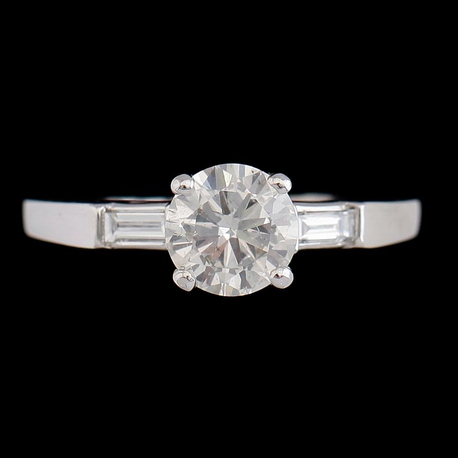 RING, 18 k vitguld, solitär briljantslipad diamant ca 1.00 ct, 2 baguetteslipade diamanter tot ca 0.16 ct.