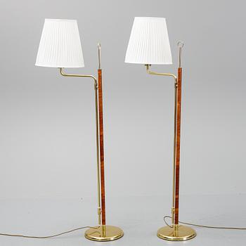 A pair of brass and leather floor lights.