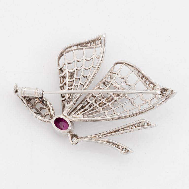 An 18K white gold brooch set with a cabochon-cut ruby and eight-cut diamonds.