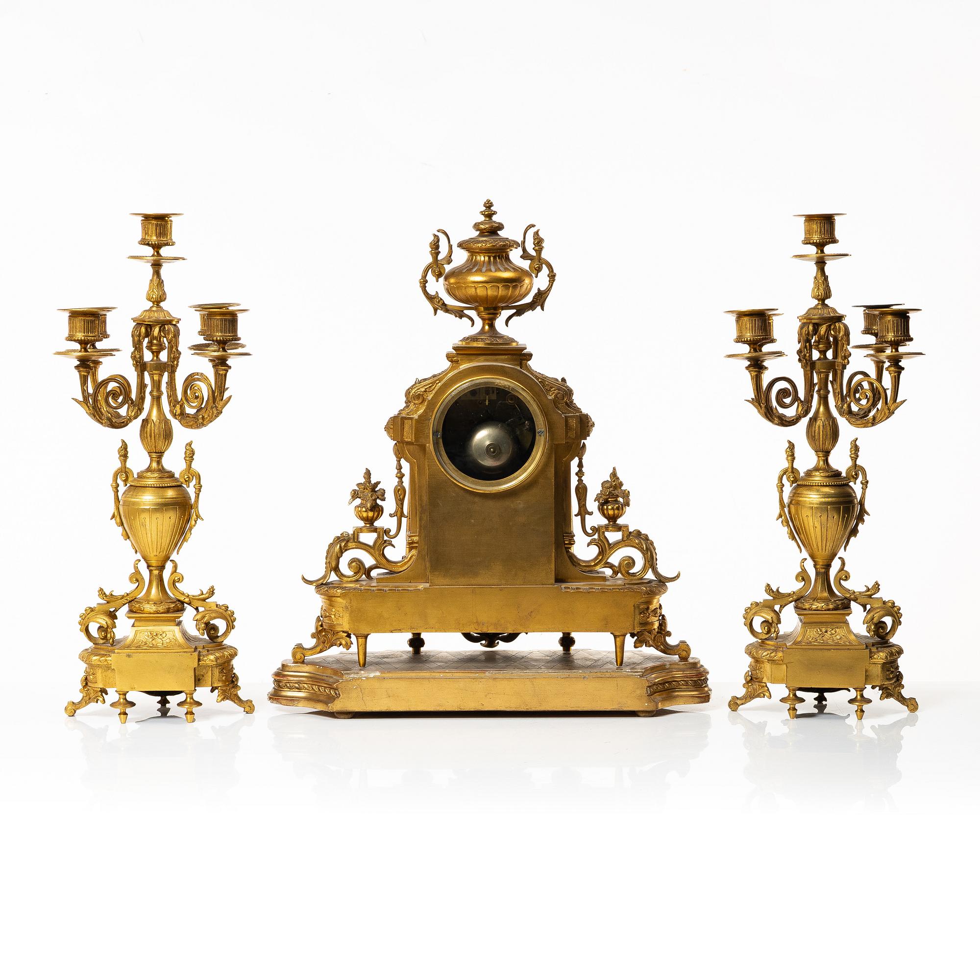 A mantle clock and a pair of candelabra, Louis XVI style, ca 1900.