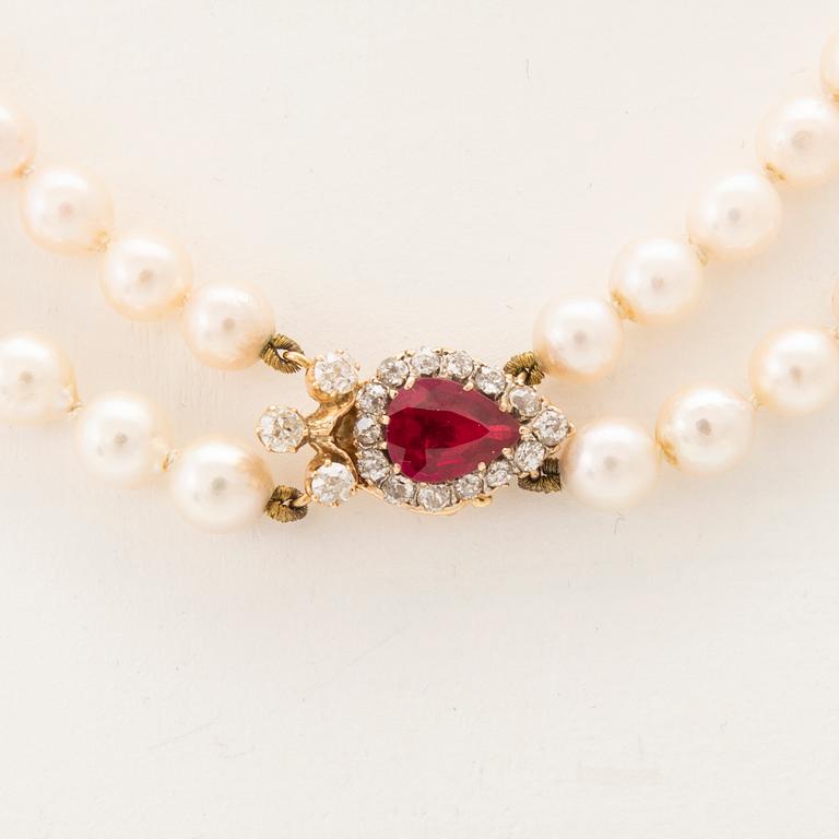 A double-stranded necklace with cultured pearls and an 18K gold clasp with a faceted synthetic ruby and old-cut diamonds.