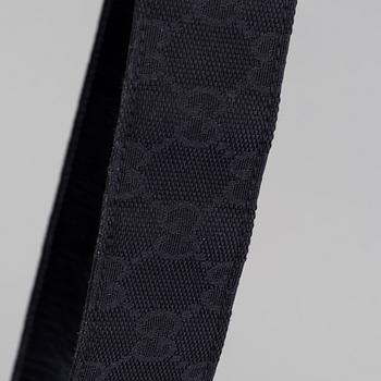 A blach monogram belt by Gucci.