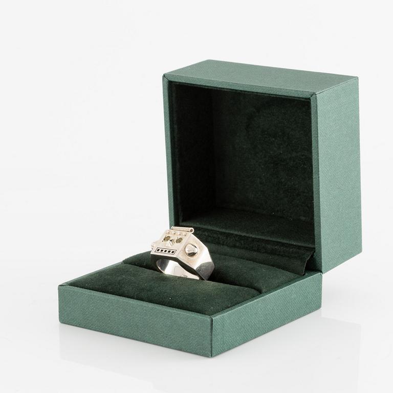 Maria Nilsdotter ring i form av ett robothuvud, sterlingsilver och gröna ögon.