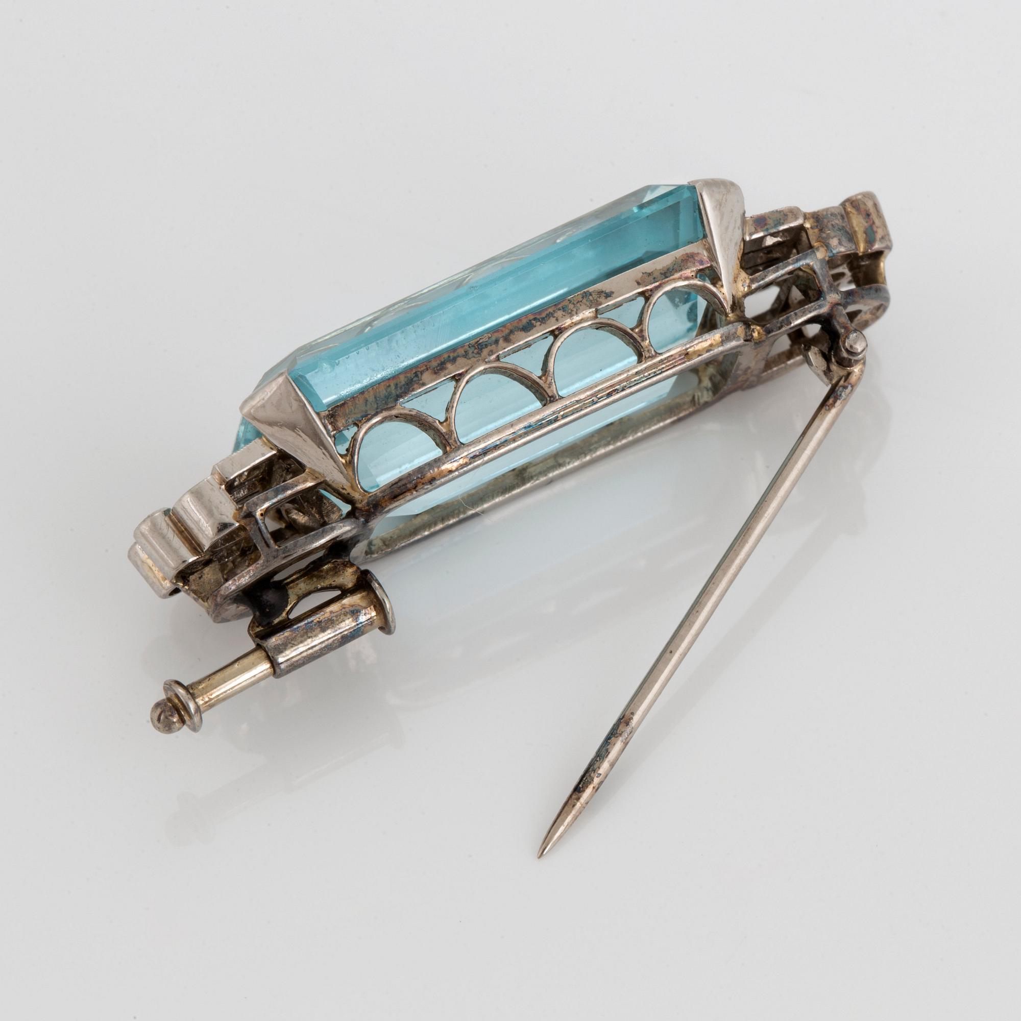 A CF Carlman brooch in 18K white gold set with a faceted aquamarine and eight-cut diamonds.