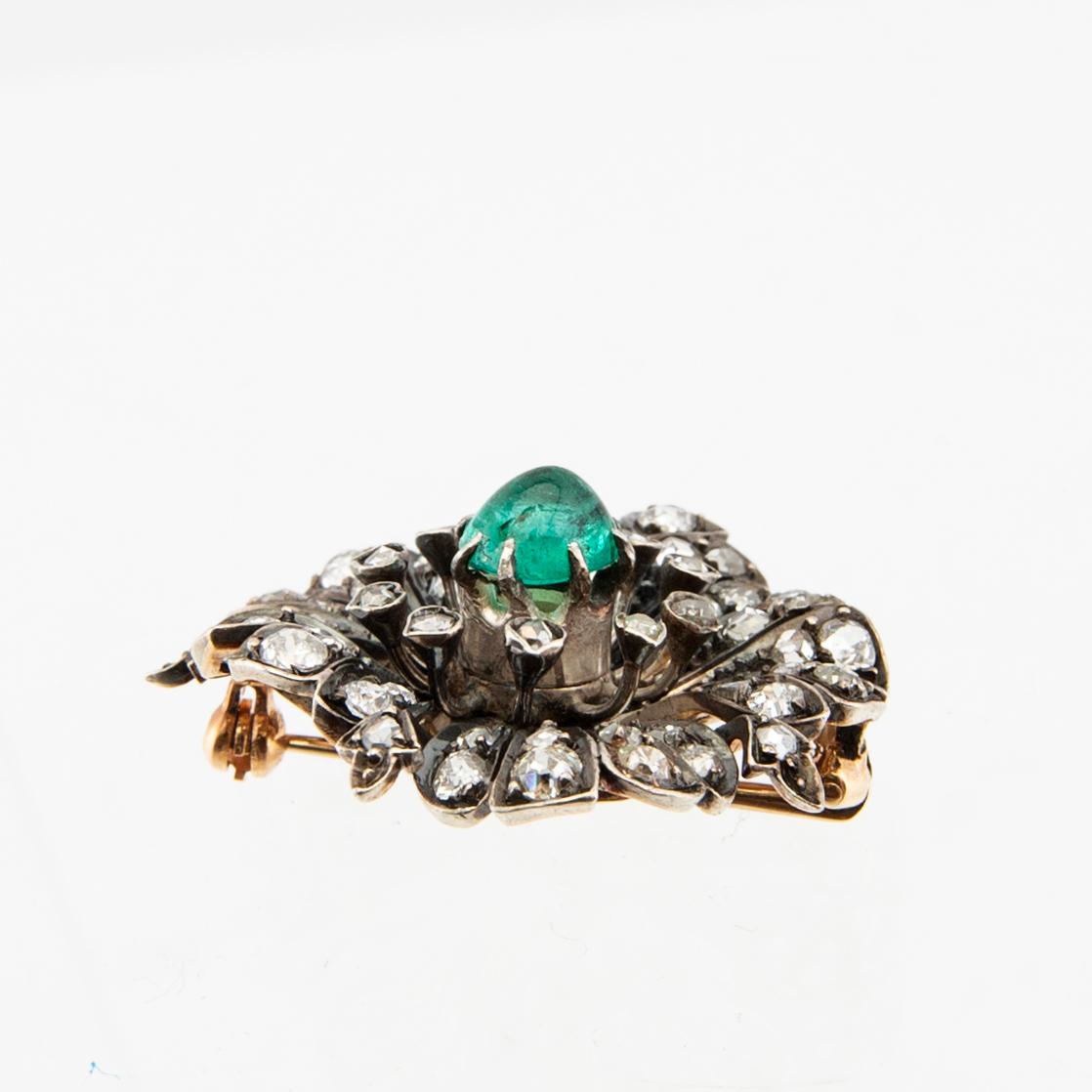 A 14K gold brooch set with a cabochon-cut emerald and old-cut as well as rose-cut diamonds.