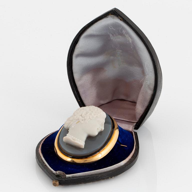 An 18K gold and black enamel brooch with a hardstone cameo.