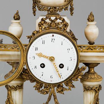 A Louis XVI-style mantle clock and a pair of candelabras. Early 20th century.