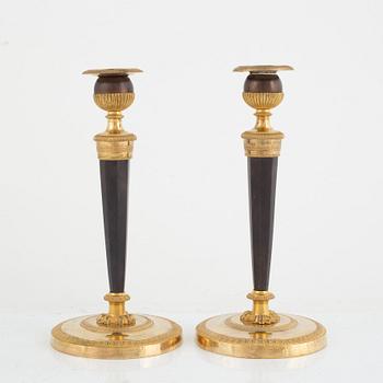 A pair of French gilt and patinated bronze Empire candlesticks, early 19th century.