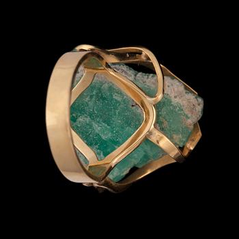 A gold ring set with an un-cut stone, probably emerald.