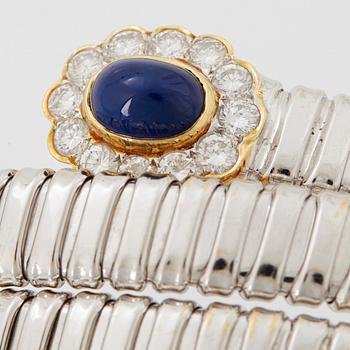An 18K gold bangle set with cabochon-cut sapphires and round brilliant-cut diamonds.