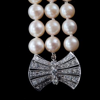 A NECKLACE, three strands of cultured pearls Ø 8 mm. Clasp in white gold and old cut diamonds c. 0.60 ct.