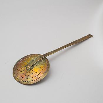 An 18th century brass strainer.