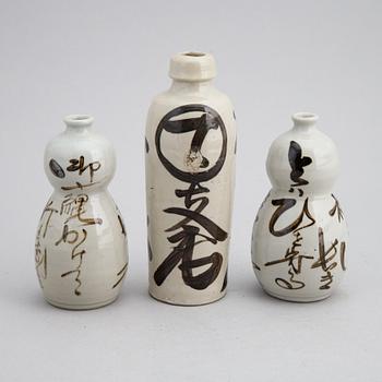 A group of twelve Japanese white glazed ceramic sake bottles, first half of the 20th century and mid 20th century.