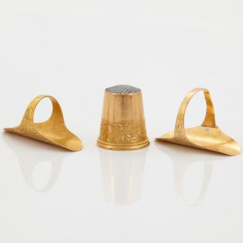 An 18K gold sew set comprising two rings and one thimble.