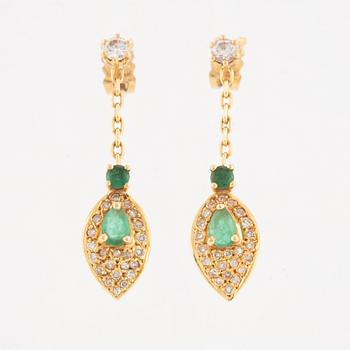 A pair of 18K gold earrings with faceted emeralds and round brilliant-cut diamonds.