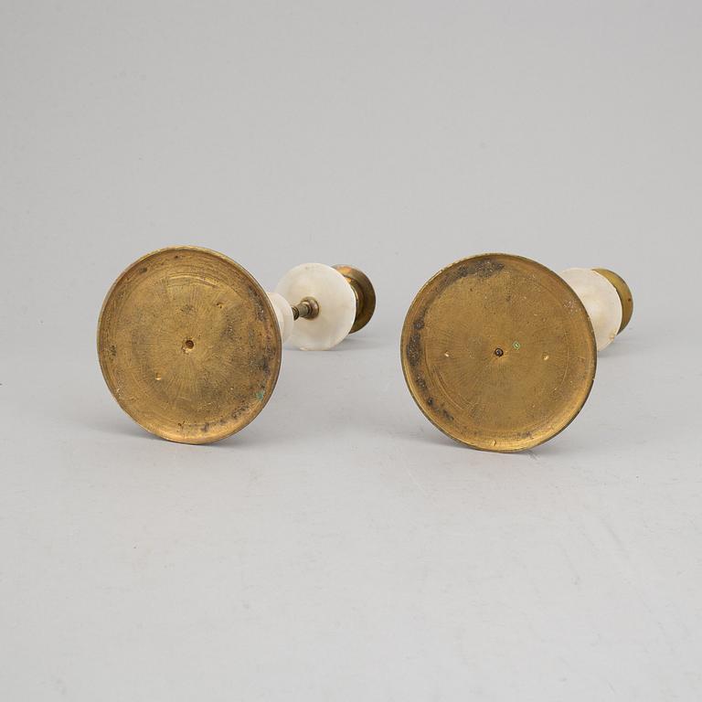 An alabaster mantle clock and pair of candlesticks, circa 1900.