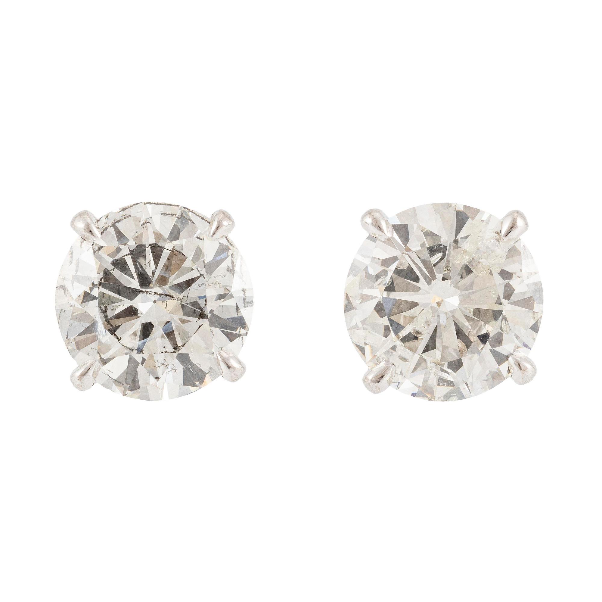 A pair of earrings in 18K white gold set with two round brilliant-cut diamonds.