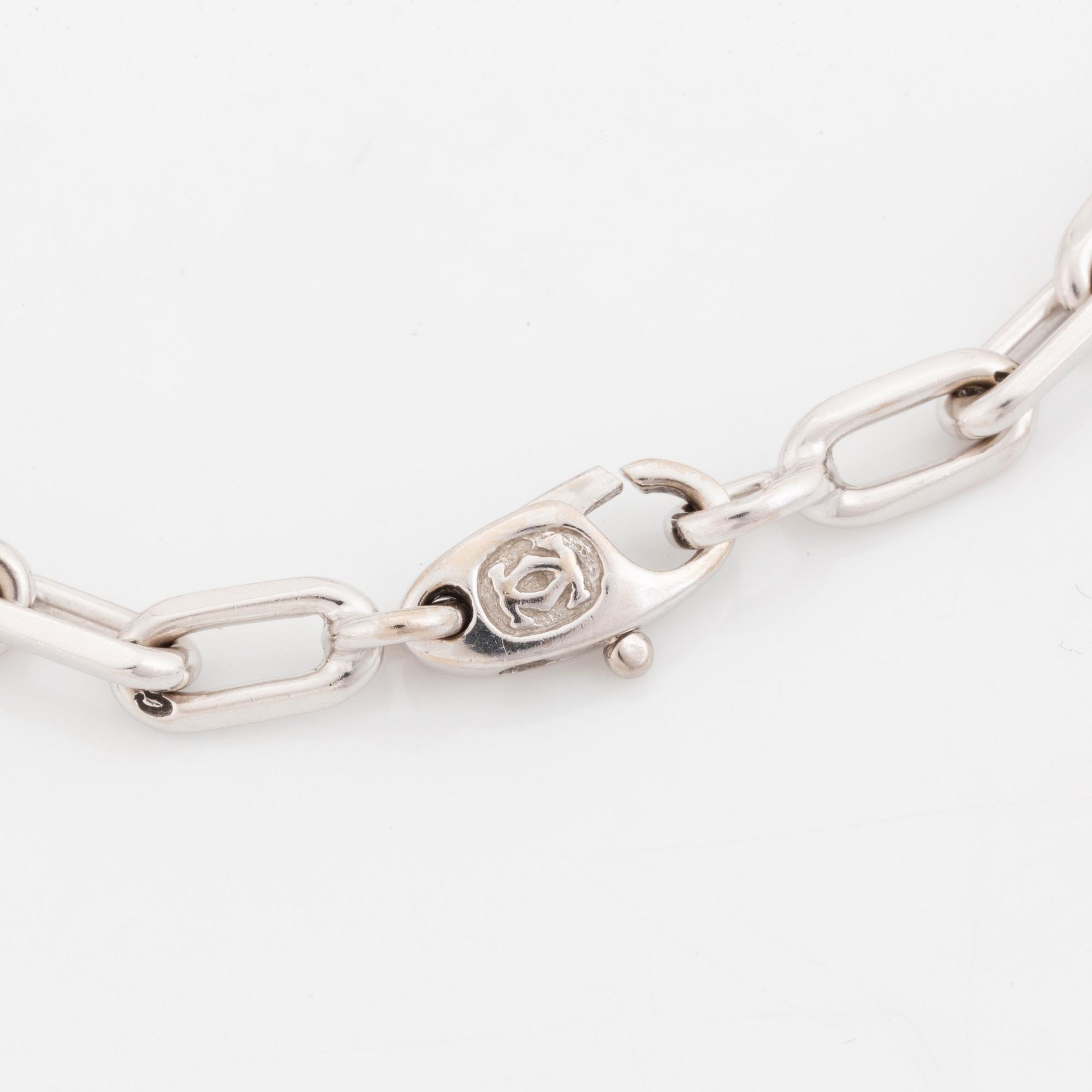 An 18K white gold Cartier "Spartacus" bracelet with two charms.