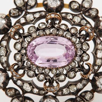 A 14K gold and silver brooch set with an oval faceted pink topaz and old- and rose-cut diamonds.