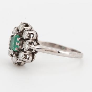 A ring set with a faceted emerald and round brilliant-cut diamonds.