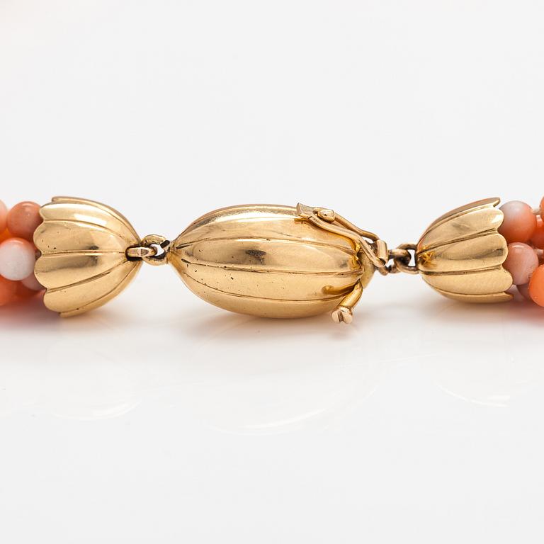 A 6-strand pearl collier with coral pearls and an 18K gold clasp.