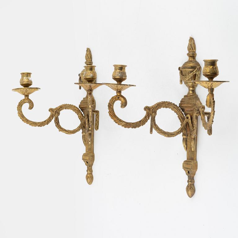A pair of brass Louis XVI-style two-light wall lights, early 20th Century.