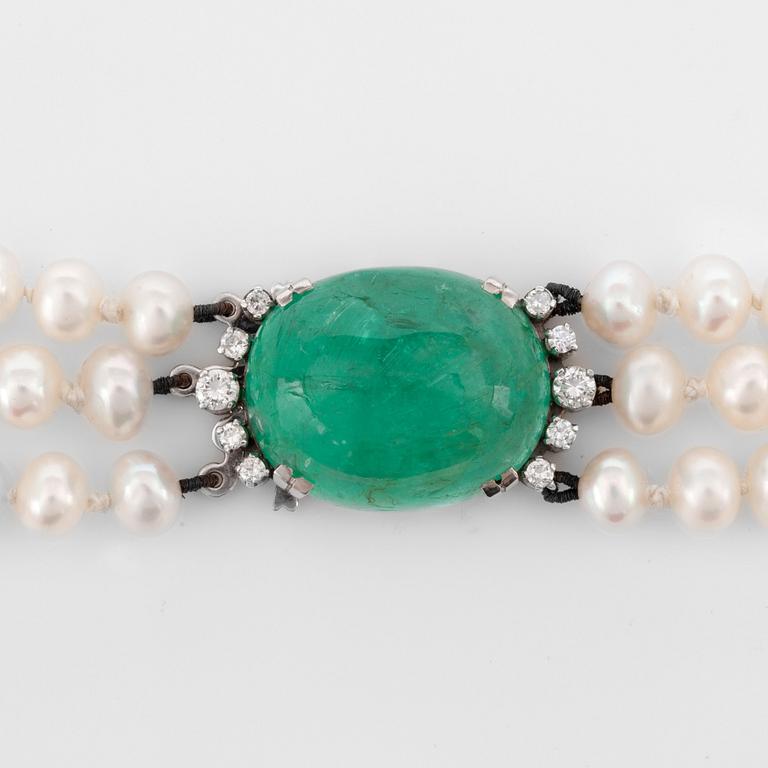 A 3-strand cultured pearl necklace. Clasp with a cabochon-cus emerald and brilliant-cut diamonds.