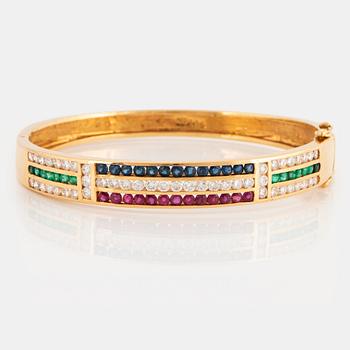 1025. An 18K gold bangle set with round brilliant-cut diamonds, sapphires, emeralds and rubies.