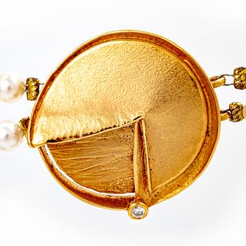 A necklace of cultured pearls and pendant in 18K gold with a brilliant cut diamond.