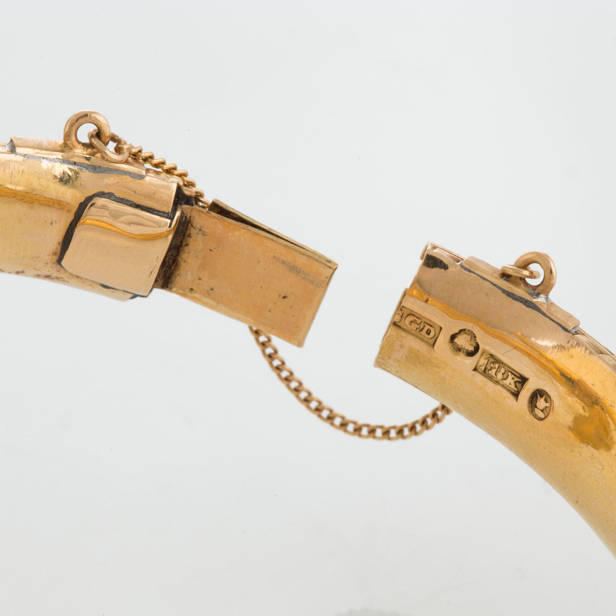 An 18K gold snake bangle decorated with blue enamel and set with an opal and a rose-cut diamond.