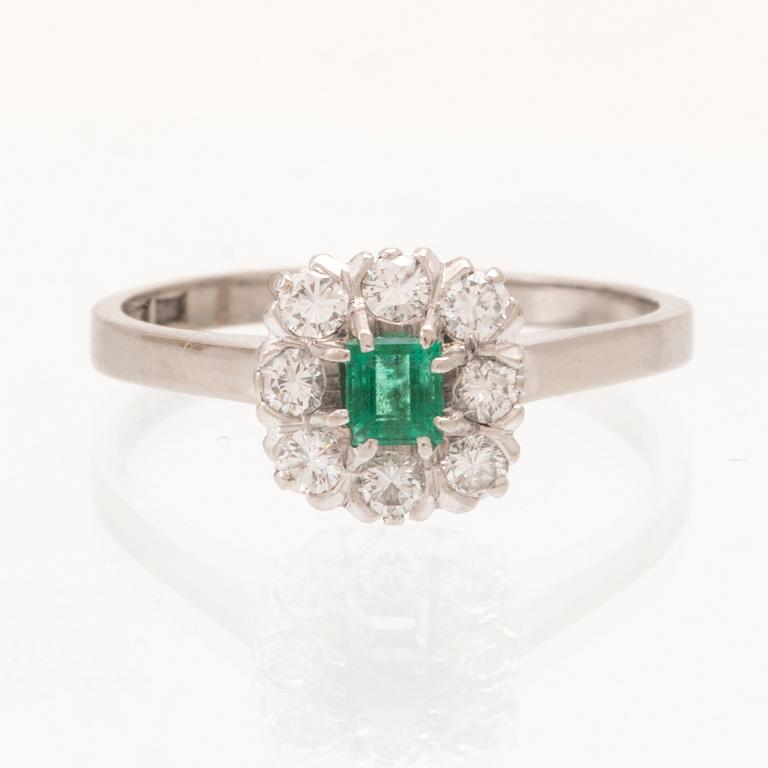 An 18K white gold ring set with a step cut emerald and round brilliant cut diamonds, Stockholm 1964.