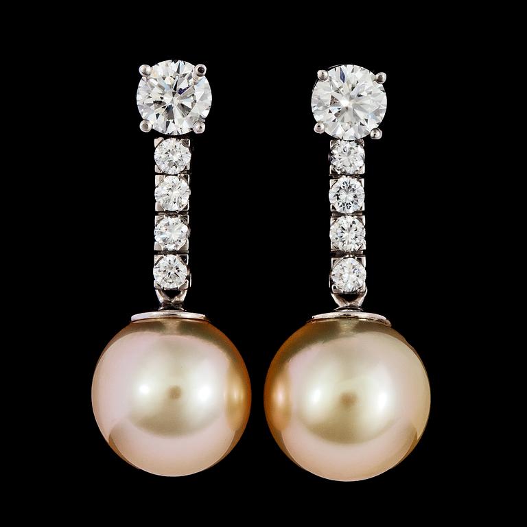 A pair odf diamond and cultured golden South sea pearl earrings, tot. app. 1.50 cts.